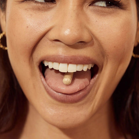 Open mouth of a woman with a pill inside